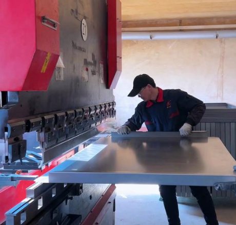 Operator bending an aluminium panel on a CNC press brake